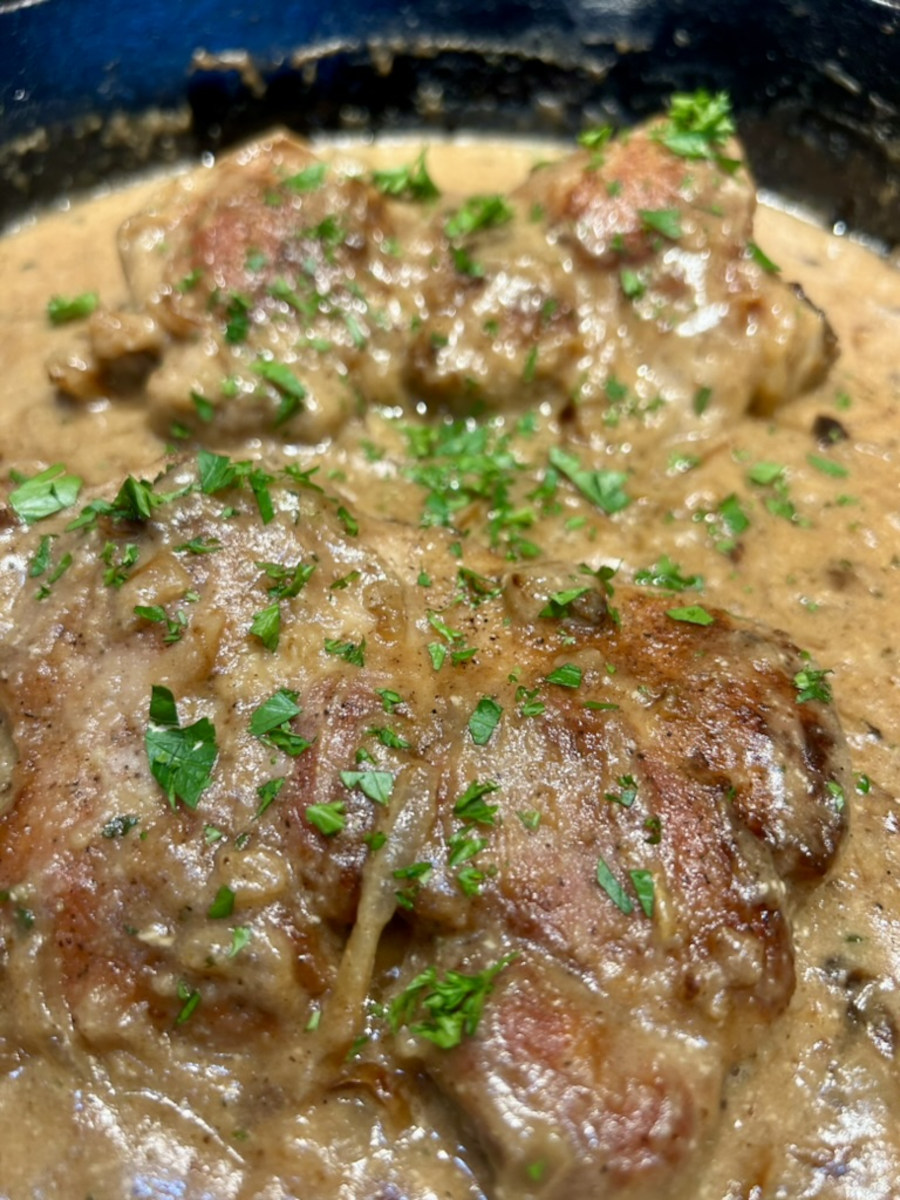 Smothered Pork Chops - in a skillet topped with chopped parsley