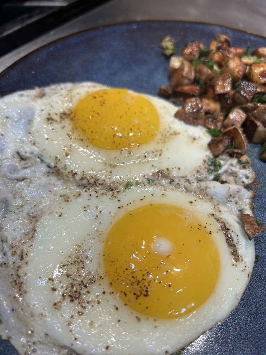 Perfect Fried Eggs - seasoned and served over-easy on a plate with breakfast potatoes