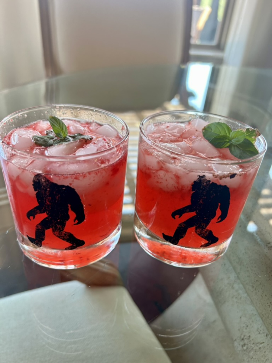Knockout Punch - Two rocks glasses with ice and red punch, garnished with a sprig of mint.