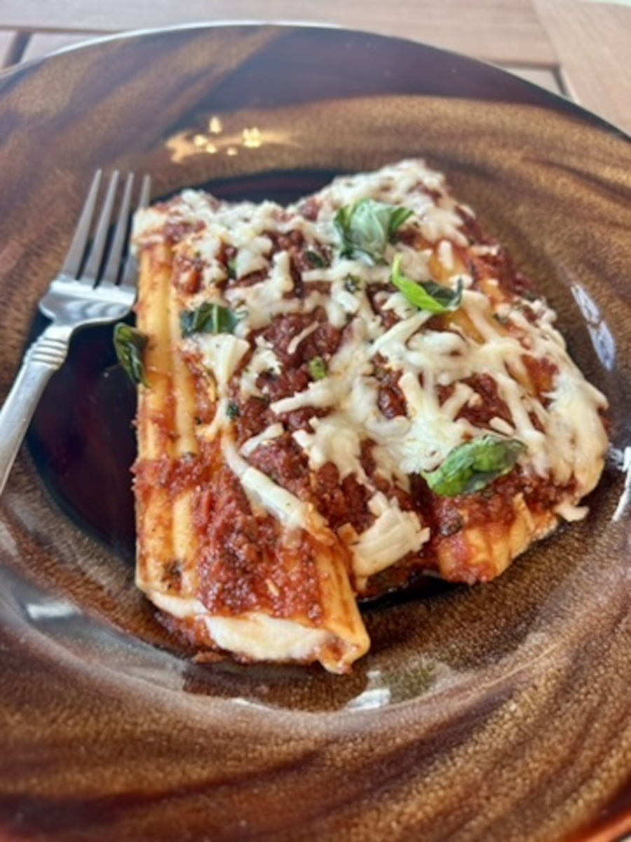 Manicotti al Ragù Americano - serve one or two stuffed manicotti noodles with extra sauce, and garnish with basil.