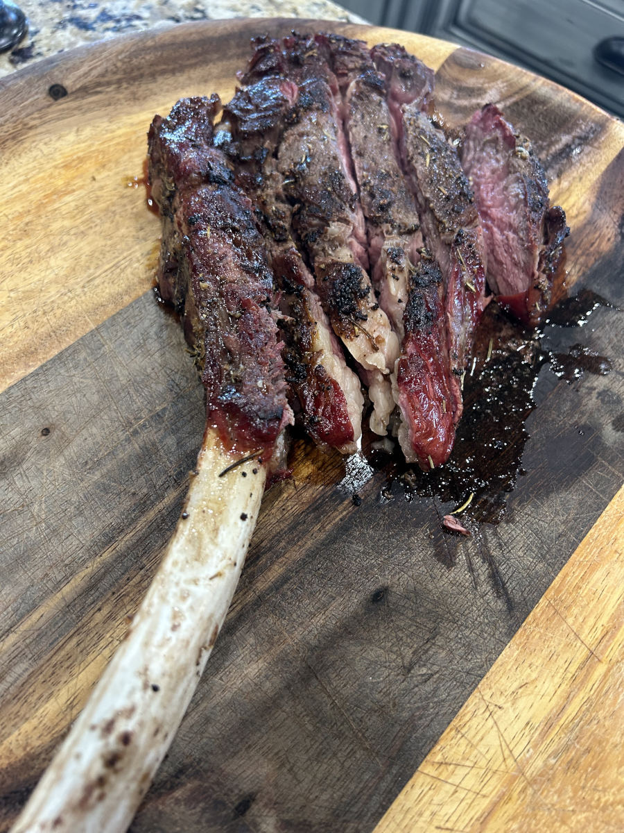 Smoked & Reverse Seared Tomahawk Ribeye - on a wooden platter, sliced and ready to serve.