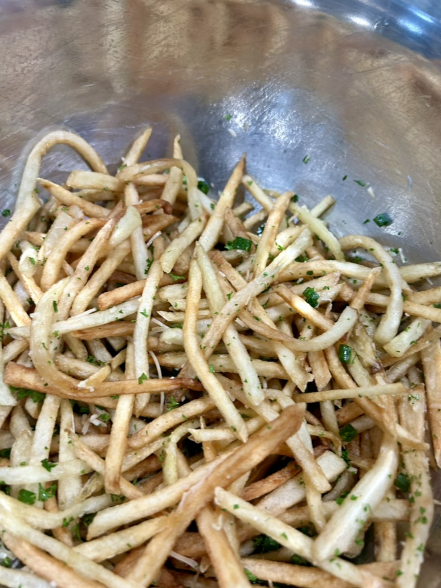 Shoestring Truffle Fries - with chopped parsley, green onions, and parmesan cheese in a large metal bowl.